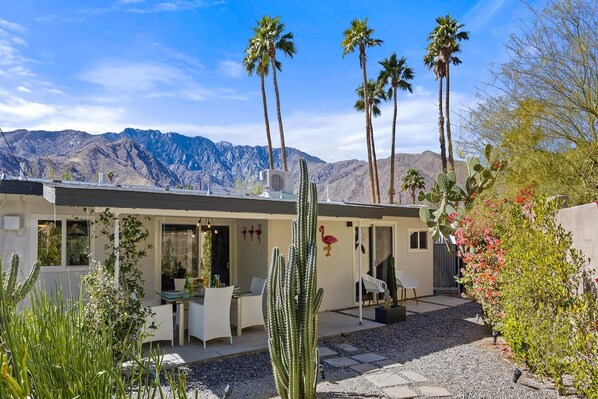 A modern house with a patio, white furniture, and cacti.