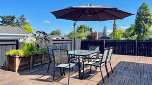 Une terrasse avec une table et des chaises, un parasol et une plateforme en bois.