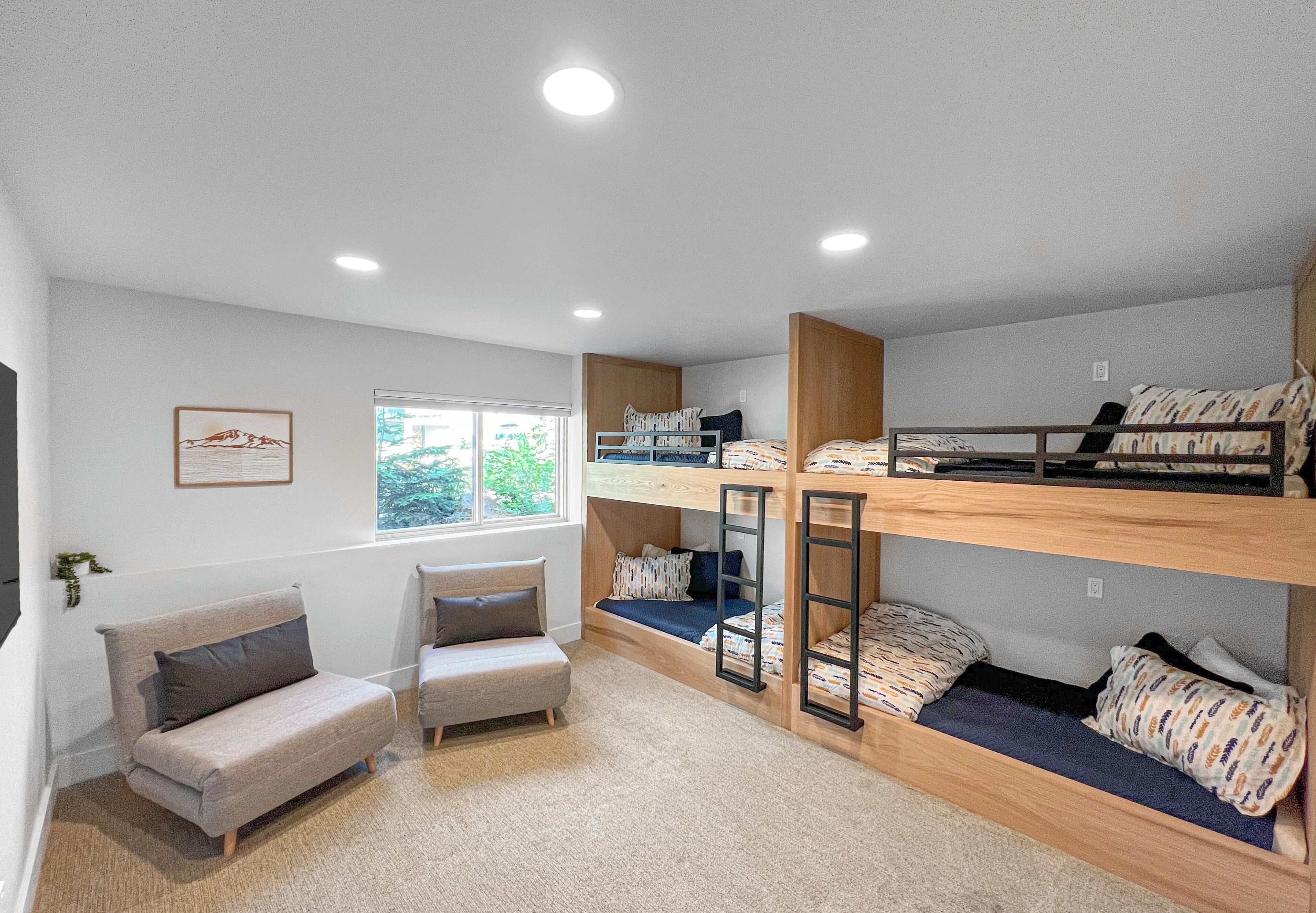 A room with bunk beds, a sofa, and a window with a view of greenery.
