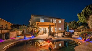 A modern house with a swimming pool, outdoor seating, and string lights. - Resort Backyard with Pool, Spa & Putting Green (Chandler)