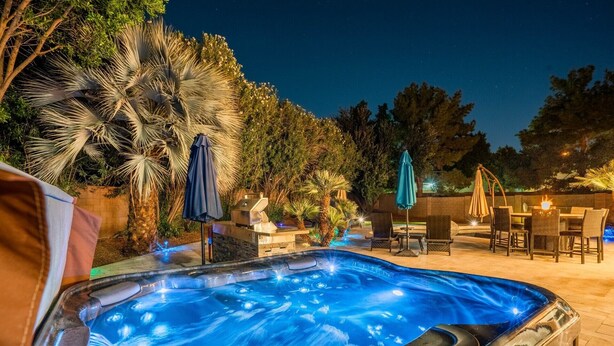 A hot tub surrounded by outdoor furniture and palm trees. - Resort Backyard with Pool, Spa & Putting Green (Chandler)