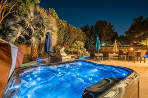 A hot tub surrounded by outdoor furniture and palm trees.