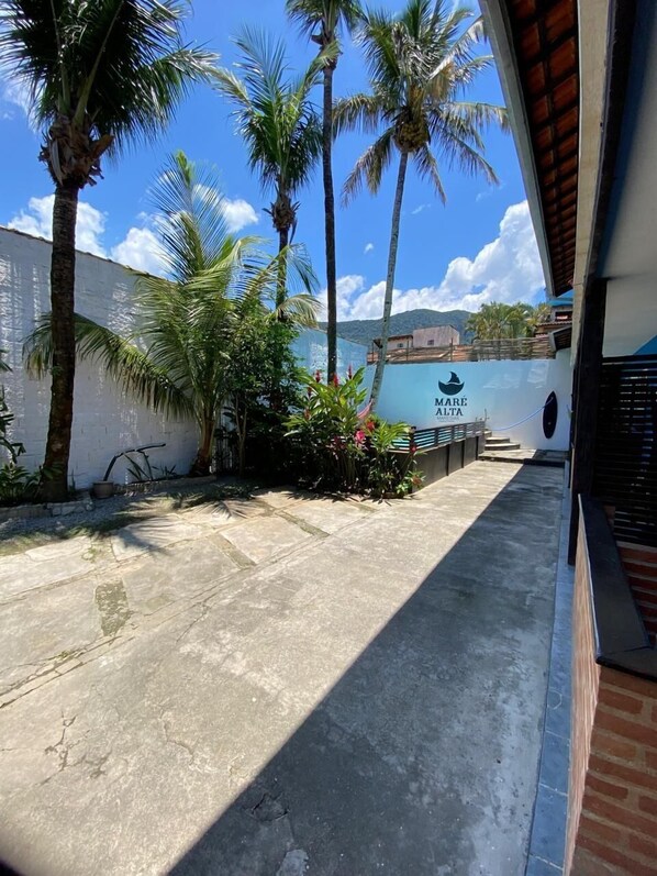 A pathway leading to a building with a white wall and a sign reading "Mare Malta." - Pousada Maré Alta (São Sebastião)