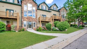 Une rangée de maisons de ville aux façades en pierre et en bois, dotées de porches et bordées d’une pelouse bien entretenue.