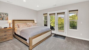 Une chambre à coucher avec un lit en bois, une table de chevet, une lampe et une fenêtre donnant sur un paysage verdoyant.