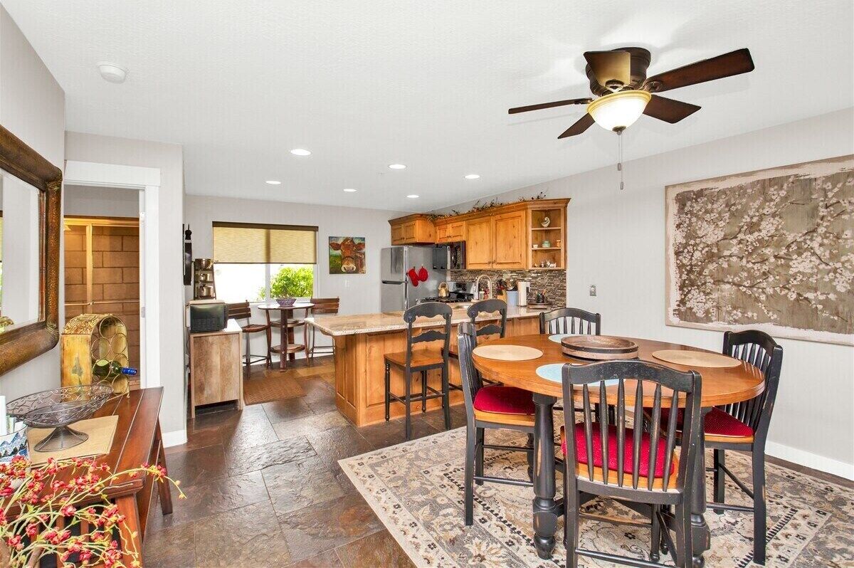A modern kitchen with wooden cabinets, a central island, and a dining area with a round table and chairs.