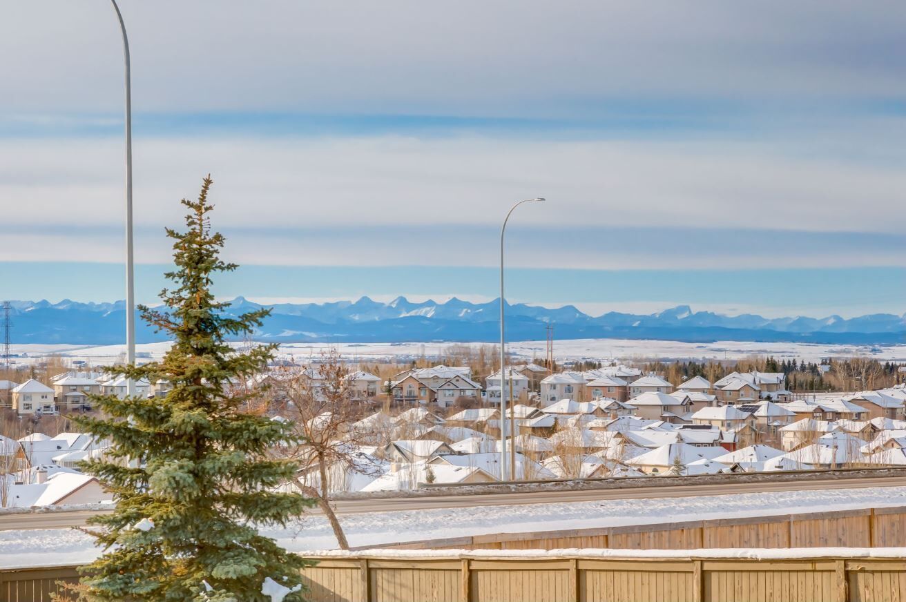 Un quartier résidentiel avec des maisons, une rue et, au loin, une chaîne de montagnes.