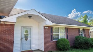 A single-story house with a white front door, a small porch, and a brick exterior. - Cheerful 3-Bed Room Home in Columbus, MS  (Columbus)