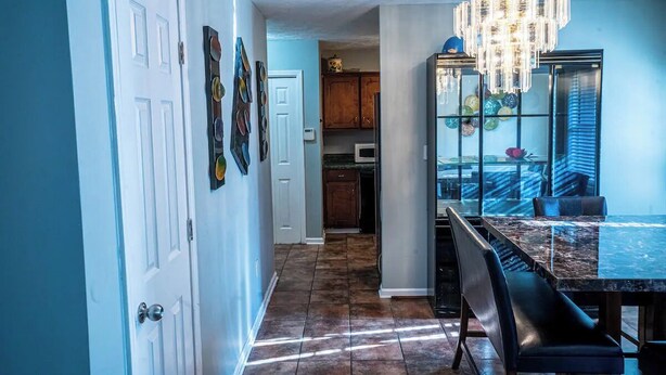 A modern kitchen with a marble countertop, a chandelier, and a dining area with a glass-top table and chairs. - Cheerful 3-Bed Room Home in Columbus, MS  (Columbus)