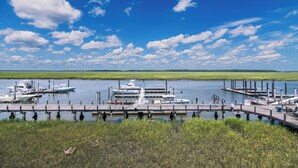 A marina with boats docked at wooden piers, surrounded by grassy areas and a clear blue sky. - 216 Bay Creek Villa-Beautiful 2nd Floor Villa;Private Balcony;Water Views;Communal Pool (Edisto Beach)