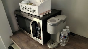 Una cocina con microondas, cafetera y dispensador de agua.