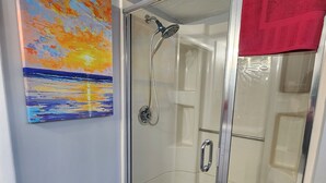 Un cuarto de baño con ducha y paredes de vidrio, con una toalla roja colgada en la puerta.