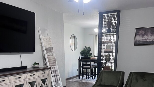 A living room with a TV, a sofa, a coffee table, and a dining area with chairs and a plant. - COZY 2Bedroom/1Bath Duplex  (Enid)