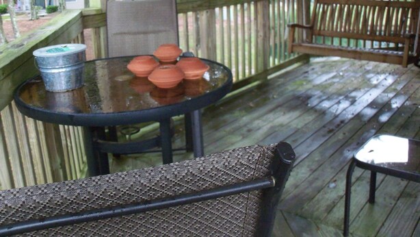 A wooden deck with a glass table and chairs, a metal bucket, and terracotta pots. - Rhue's Haven less than 5 minutes from the most wonderful beach in NC (Sunset Beach)