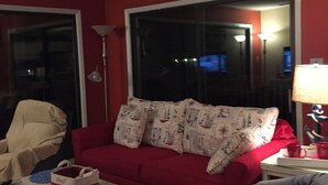 A living room with a red couch, a white coffee table, a red armchair, and a ceiling fan. - Rhue's Haven less than 5 minutes from the most wonderful beach in NC (Sunset Beach)