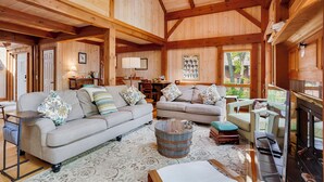 A cozy cabin interior with two sofas, a wooden coffee table, and a fireplace.