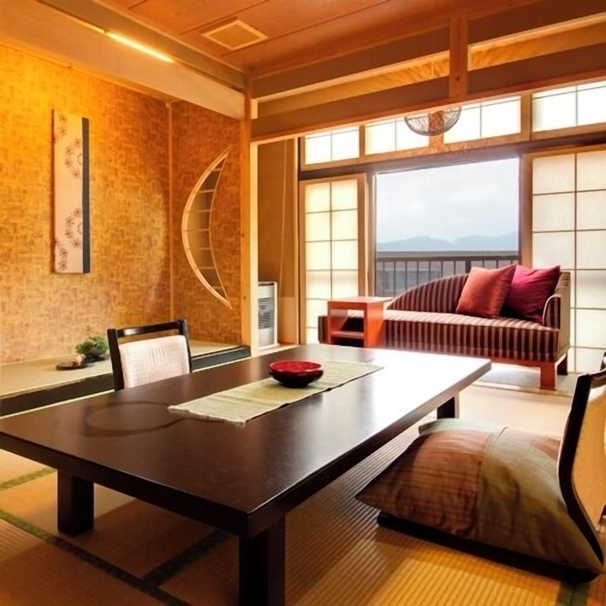 A traditional Japanese room with tatami flooring, a low table, a sofa with cushions, and a view through large windows.
