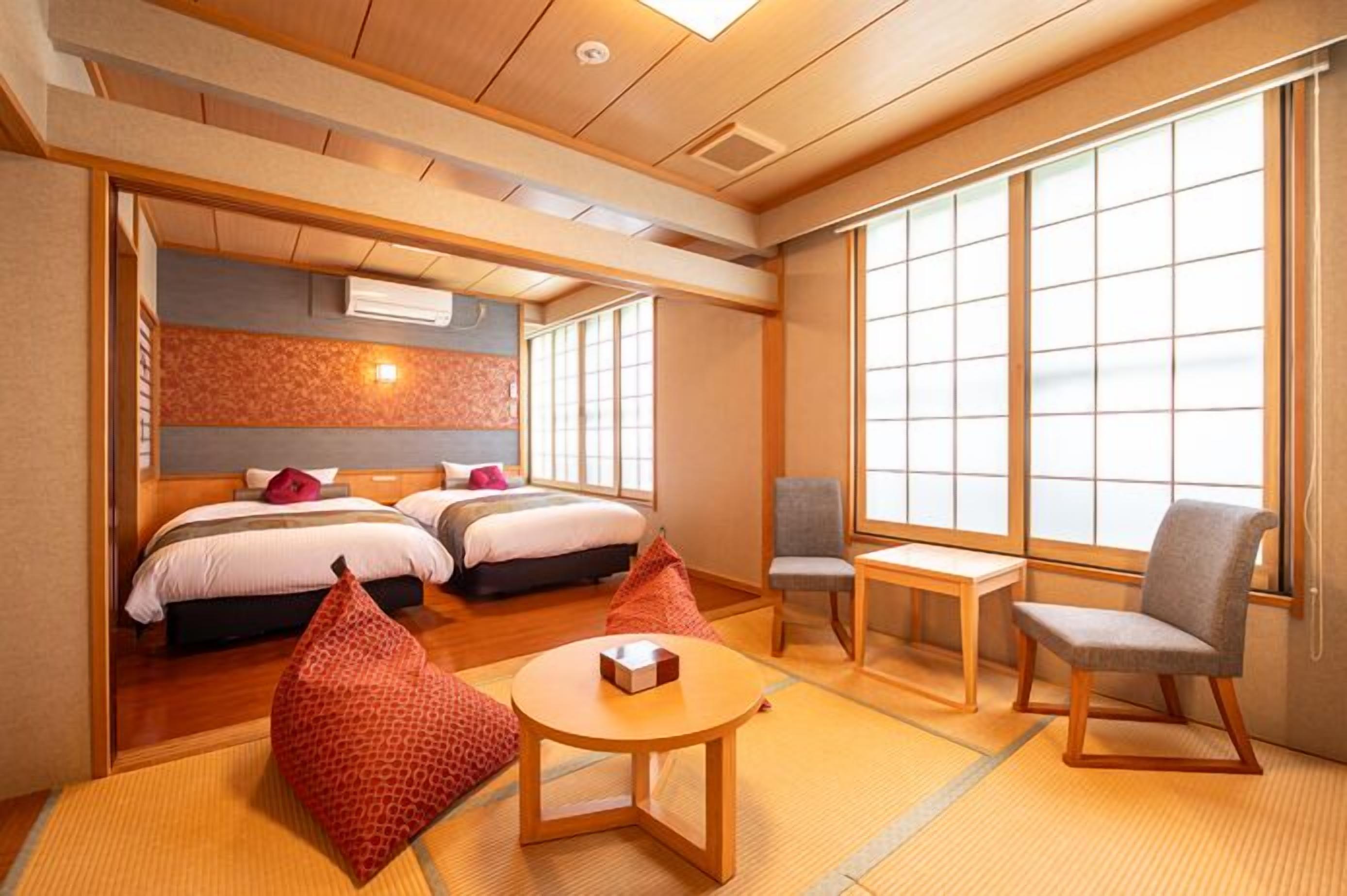 Habitación de hotel de estilo japonés tradicional, con suelo de tatami, futón, una pequeña mesa y una silla.