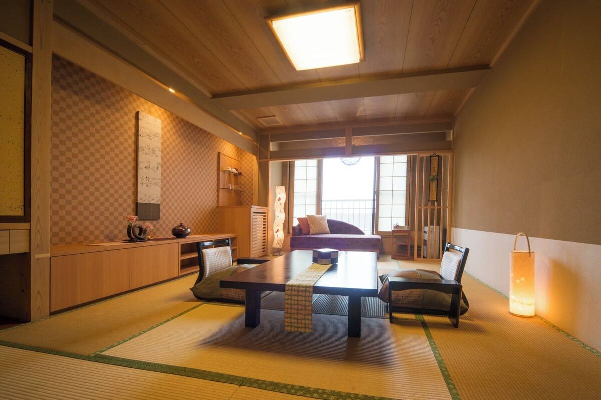 A traditional Japanese room with tatami flooring, a low table, and a sofa.