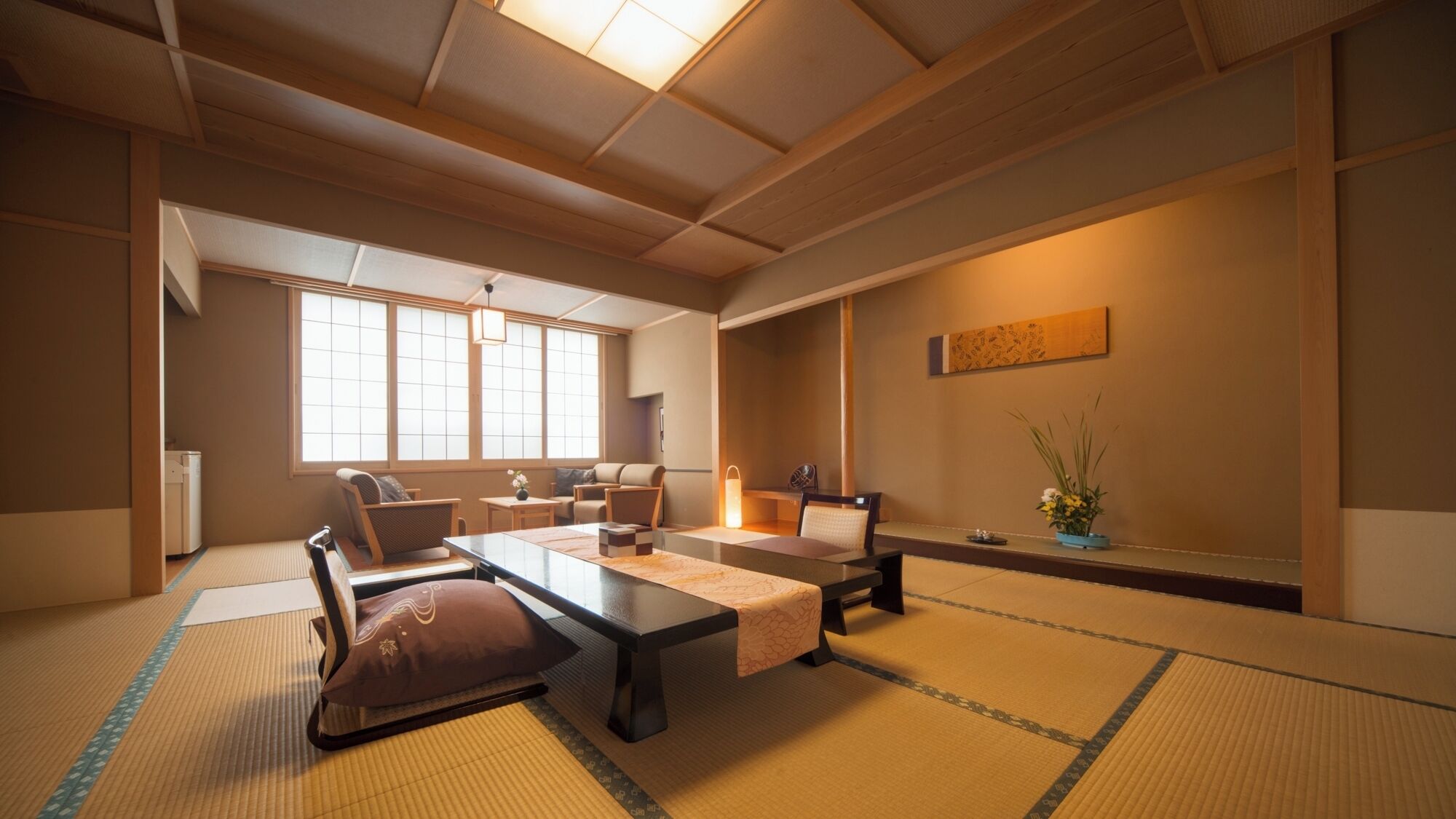 Una habitación tradicional japonesa con suelo de tatami, una mesa baja y disposición de asientos.