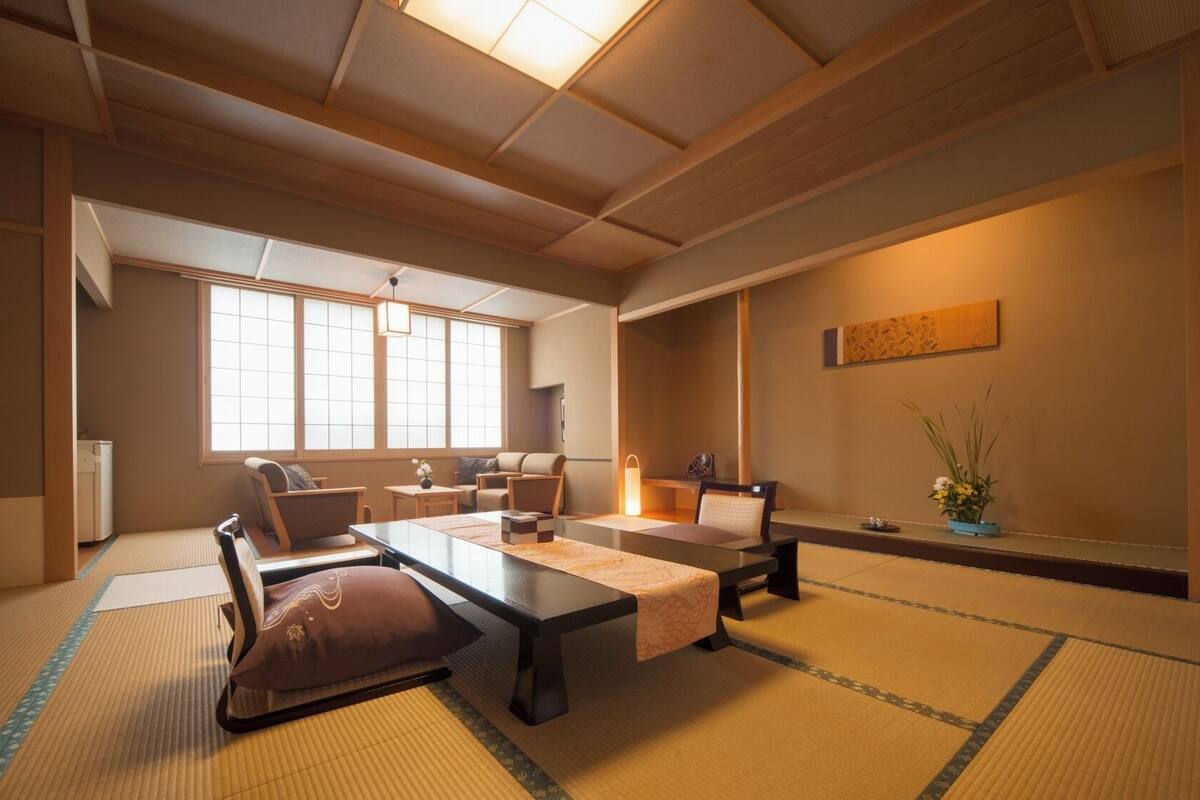 A traditional Japanese-style room with tatami flooring, a low table, and seating arrangements.