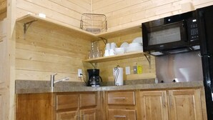 Una cocina compacta con gabinetes de madera, microondas y cafetera.