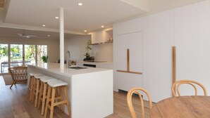 Eine moderne Küche mit einer zentralen Kochinsel, Barhocker und Holzsesseln.