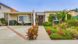 A two-story house with a front porch, a garage, and a well-maintained garden with various plants and flowers. - 50 ft from the SAND 30 seconds (Del Mar)