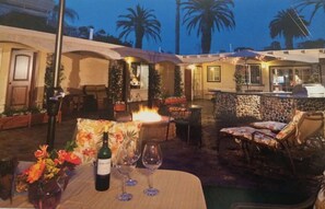 An outdoor patio with a fire feature, seating, and a bar area.