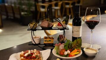A dining table with a bottle of wine, a wine glass, and various dishes including a sandwich, salad, and a dessert.
