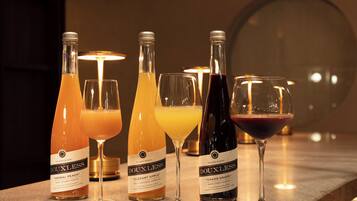 A bar setting with three bottles of Douxless beverages and three glasses, each containing a different drink.