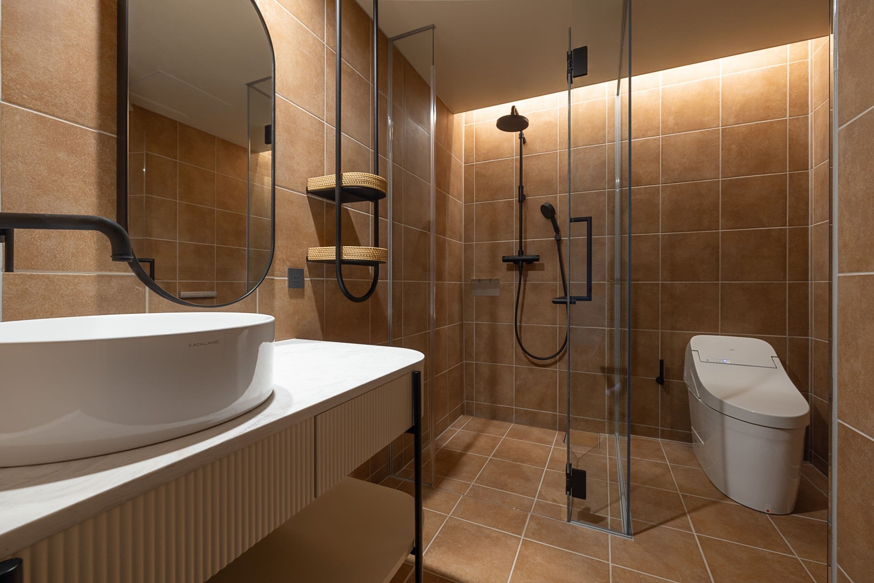 A modern bathroom with a large white sink, a glass shower enclosure, and a white toilet.