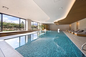 A modern indoor swimming pool with clear glass walls, a tiled floor, and a wooden ceiling. - nol hakone myojindai (Hakone)