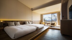 Een moderne hotelkamer met twee grote bedden, een zithoek en uitzicht op bergen.