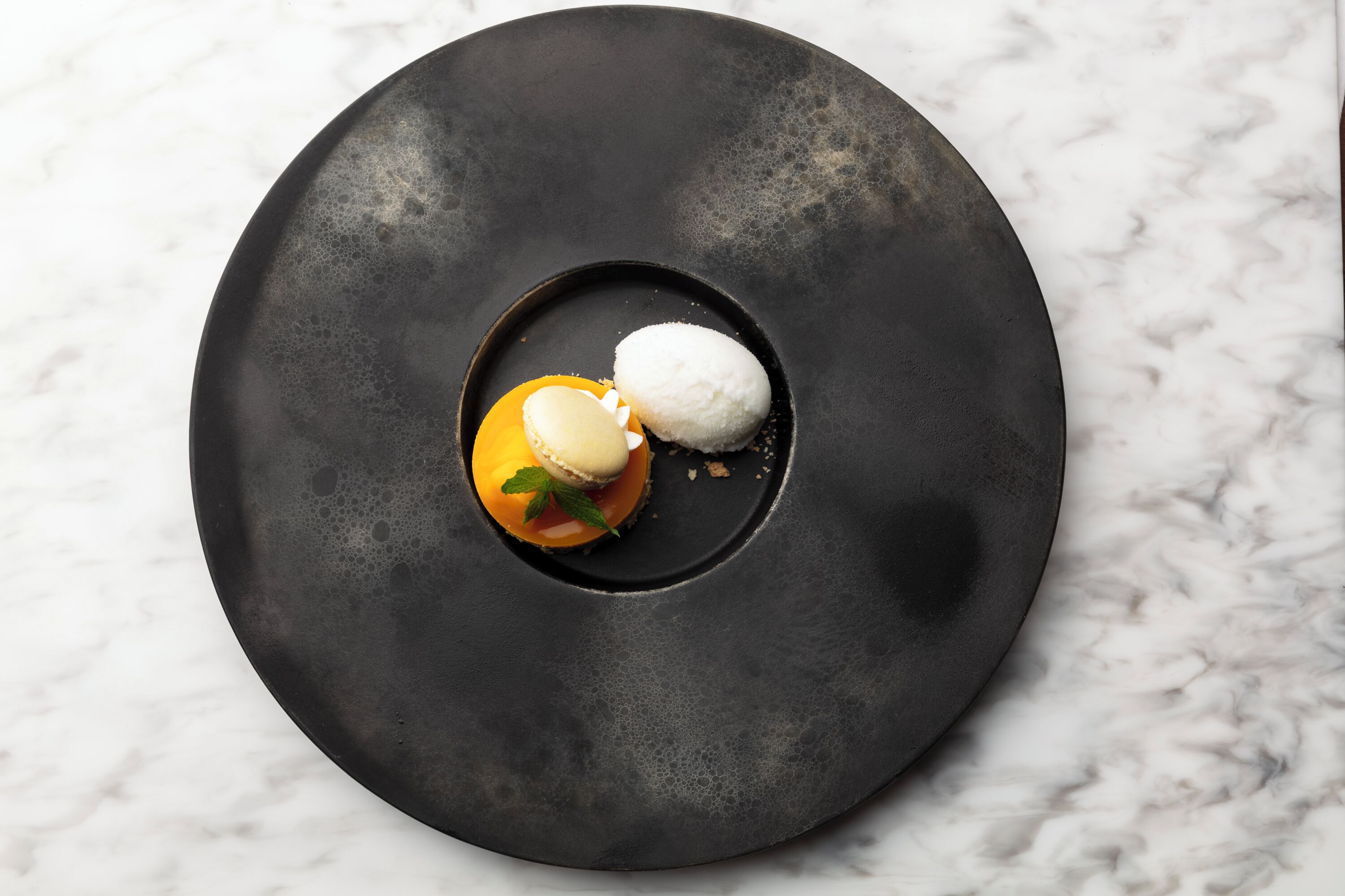 A dessert on a black plate with a marble background.