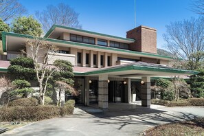 A two-story building with a green roof and brick facade, featuring a covered entrance with columns and a small porch area. - nol hakone myojindai (Hakone)