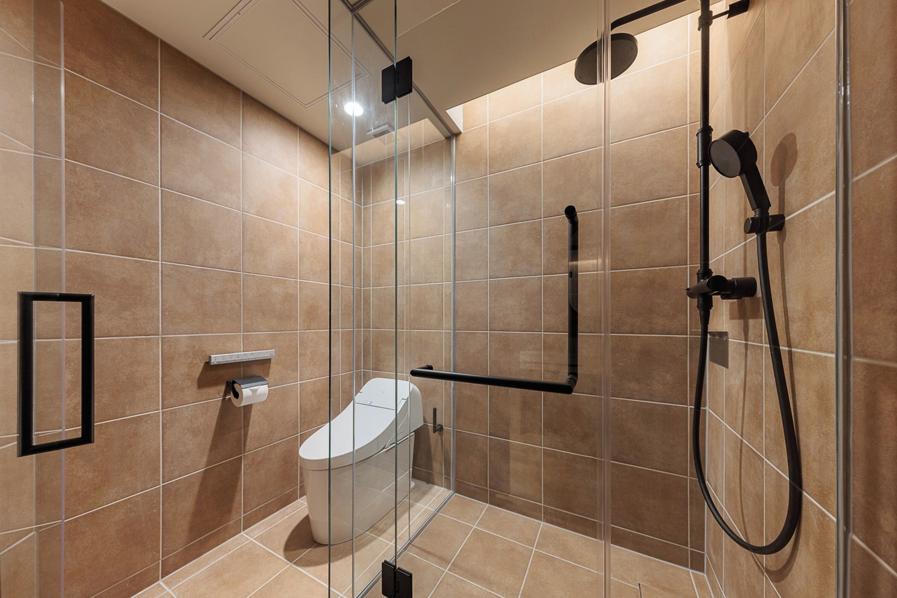 Ein modernes Badezimmer mit einer Duschkabine, einer Toilette und einem Handtuchhalter.