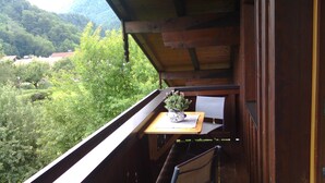 Un balcón con una mesa de madera, una silla y una planta en maceta.