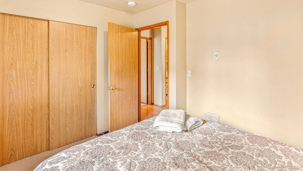 A bedroom with a bed, a wooden wardrobe, and a door leading to another room. - Alpine Oasis in Leavenworth (Leavenworth)