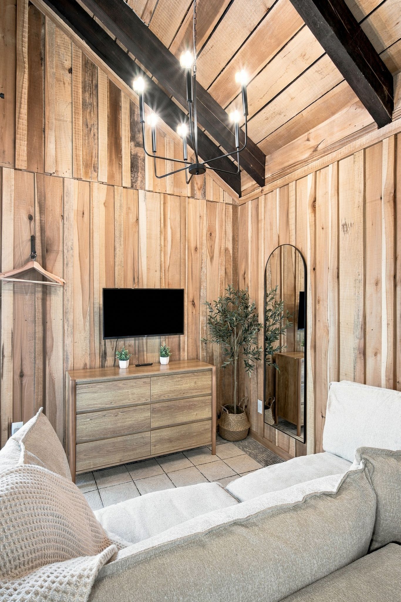 Habitación con paneles de madera, un sofá, un televisor, un aparador y un espejo.
