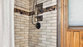 A shower with a stone mosaic wall, a bench, and a wooden door.