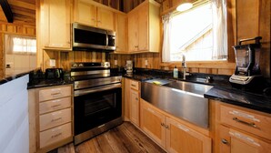 Une cuisine avec des meubles en bois, des appareils électroménagers en acier inoxydable et une fenêtre avec des rideaux.