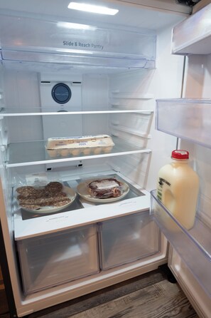A refrigerator with a 'Slide & Reach Pantry' label, containing eggs, meat, and a milk carton. - Family-Friendly Creekside Cabin, Space to Roam + Play (Smithville)