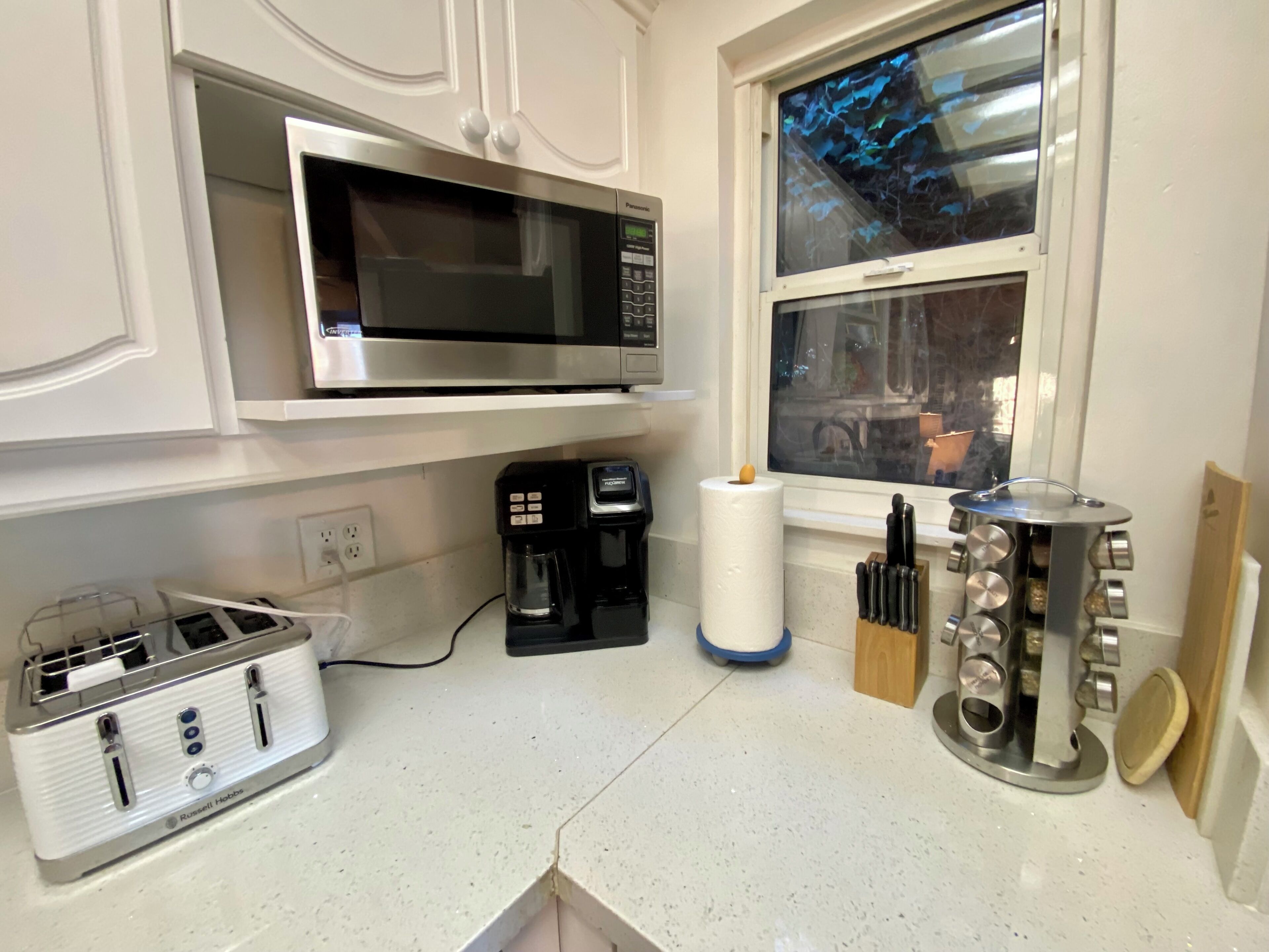A kitchen with a microwave, toaster, coffee maker, and a knife block.