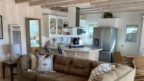 A modern living room with a brown sectional sofa, a coffee table, and a kitchen area in the background.