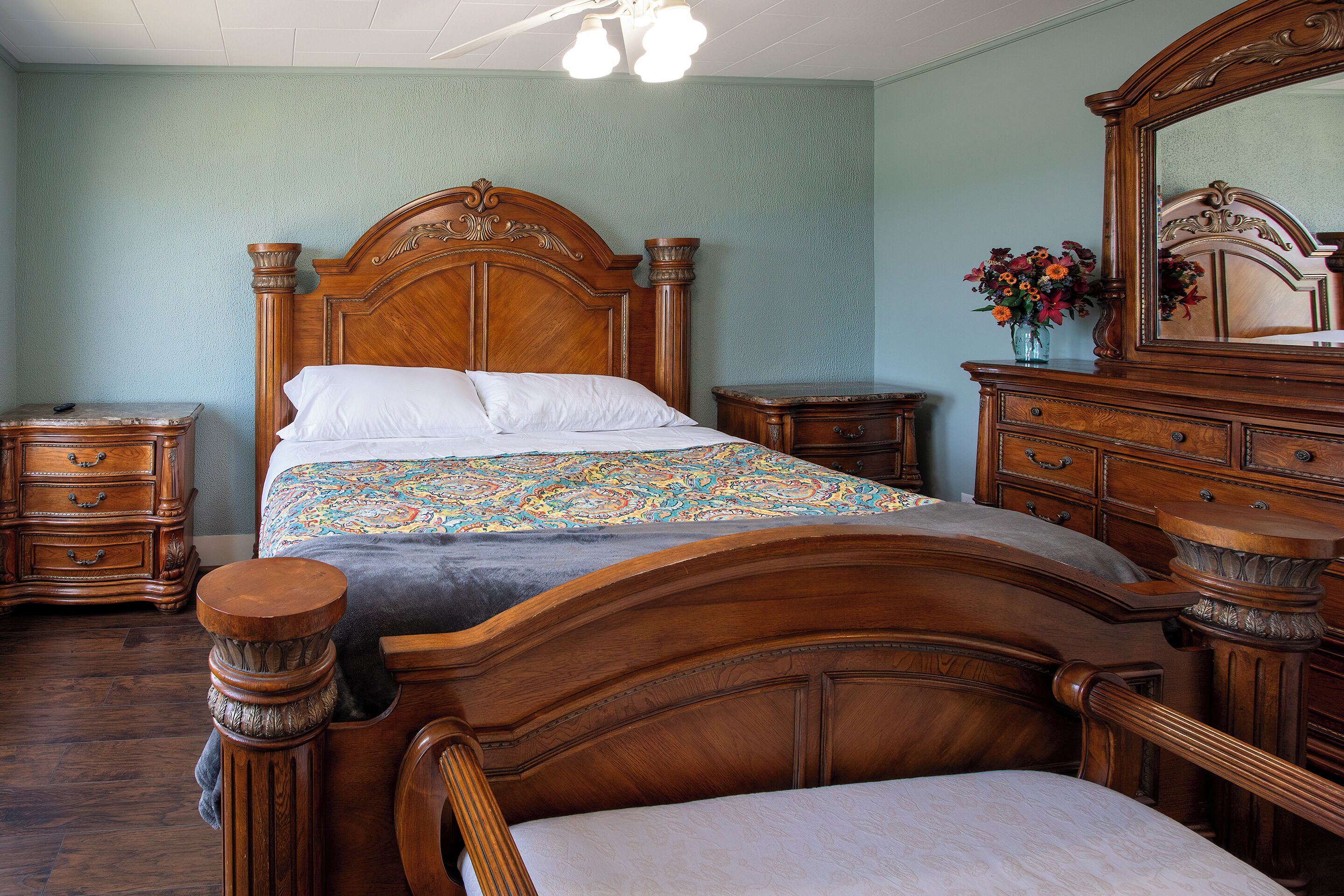 Une chambre à coucher de style traditionnel, avec un lit en bois, une commode et un miroir.