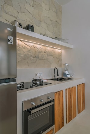 Una cocina moderna con un refrigerador LG integrado, estufa a gas, horno empotrado y armarios de madera.