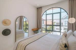 Ein Schlafzimmer mit einem großen Bett, einem Spiegel und Blick durch ein großes Fenster nach draußen.