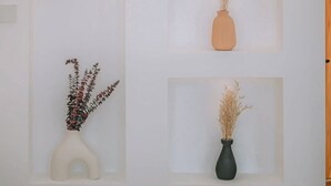 Un mur avec trois étagères, chacune portant un vase différent contenant des plantes séchées.