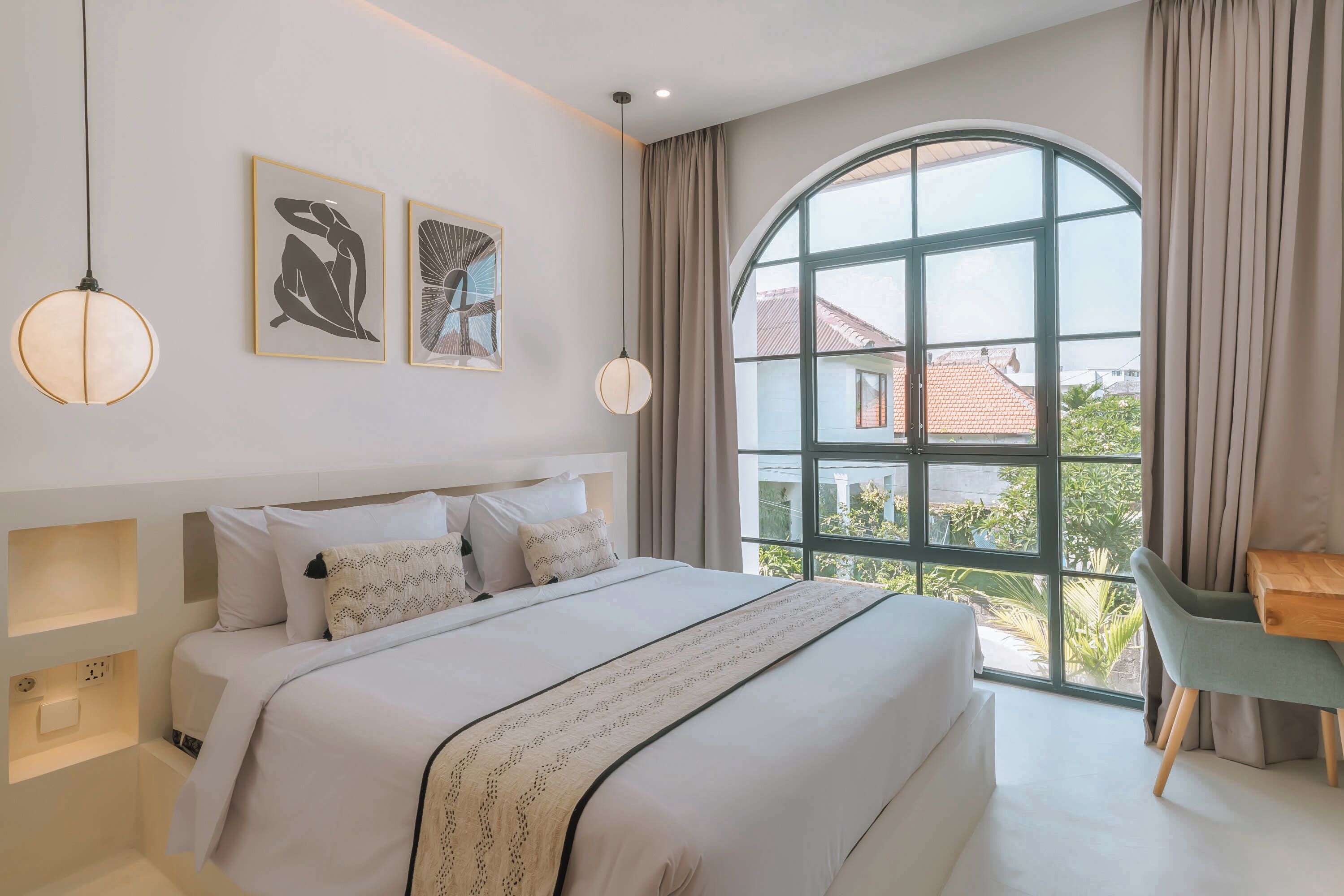 A bedroom with a large bed, a desk, and a window with curtains.